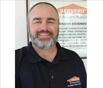 male employee wearing a black SERVPRO shirt standing in front of a SERVPRO sign
